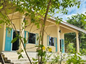 una piccola casa gialla con porte blu di Baya Beach Club 