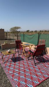 a picnic table and two chairs on a rug at Jabreen Castle Camp in Naţţālah +15 photos