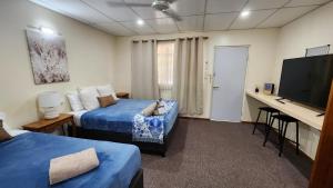 Habitación con 2 camas, escritorio y TV. en Gold City Motel, en Charters Towers