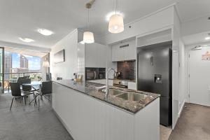 a kitchen with a large counter and a dining room at Evolve Apartments Brisbane in Brisbane