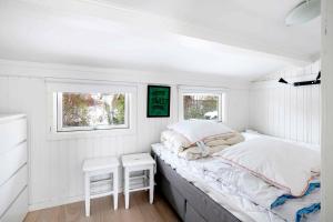 RødvigにあるLovely Bright Summer House Close To The Beachのベッドとテーブルと2つの窓がある寝室