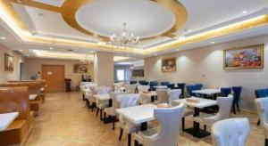 a restaurant with white tables and chairs and a chandelier at Vienna Hotel Jinan Railway Station in Jinan