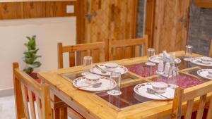 a wooden table with plates and cups on it at Monal Homestay in Kulu +12 photos