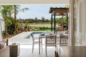 comedor con mesa, sillas y piscina en Luxury Golf Villa at Azuri - with beach access, en Roches Noires