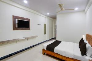 a bedroom with a bed and a tv on the wall at Hotel O Khammam Railway Junction Formerly Raghavendra Inn in Khammam