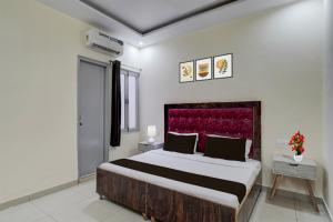 a bedroom with a large bed with a red headboard at Hotel O Meerut Central College Formerly Saffron in Meerut
