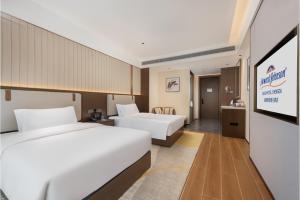 a hotel room with two beds and a television at Howard Johnson by Wyndham Zun Ju Hotel Cheng Du in Xindu