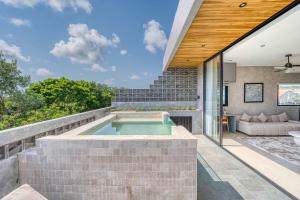 an outdoor patio with a swimming pool and a house at Elourea 1BR Apt Rooftop Jacuzzi In Uluwatu in Uluwatu