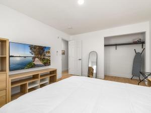 a white bedroom with a large tv on the wall at Casitas en Pueblo - Central Lofts in Pueblo