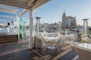 a balcony with white tables and chairs on a building at Room Mate Oscar, Madrid in Madrid
