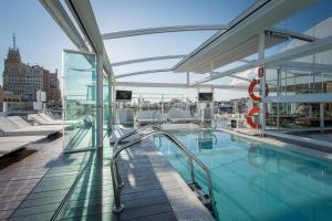 a large swimming pool in a building with a balcony at Room Mate Oscar in Madrid