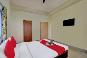 a bedroom with a bed with red pillows and a television at Hotel O Tumpa Inn in Kolkata +22 photos