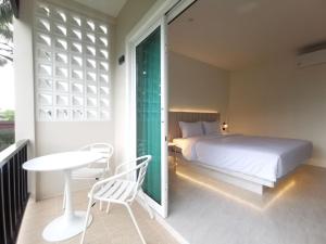 a bedroom with a bed and a table and chairs at The Pinda House Bangtao in Bang Tao Beach