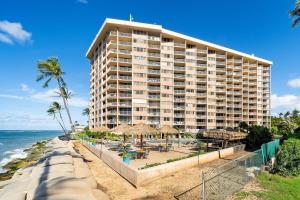 a large building on the beach with chairs and umbrellas at Royal Kahana 909 · RK 909 OceanFront Condo w Beautiful Ocean Vie in Kahana