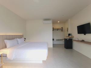 a bedroom with a white bed and a flat screen tv at The Pinda House Bangtao in Bang Tao Beach