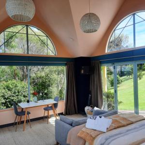 a bedroom with large windows and a bed and a table at The Quarters Ocean-View Chalet in Gisborne