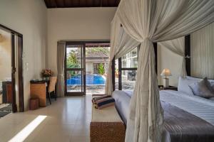a bedroom with a canopy bed and a pool at 3Bedroom Umasari Villa in Keramas