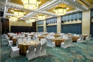 a large banquet hall with tables and white chairs at Hundred Hotel Qingdao in Qingdao