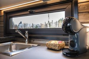 Una cafetera en la encimera de la cocina junto a un fregadero. en Aava Riverside, en Rovaniemi 50 fotos más