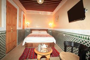 a hotel room with a bed and a table and a tv at Riad Moulay Spa in Marrakech