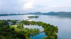 an island in a lake with a city in the background at Magnotel Business Xuzhou Jinying Sudi Road Metro Station in Xuzhou