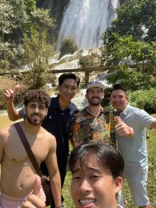 a group of men standing in front of a waterfall at Mai Chau Hostel in Mai Chau +21 photos