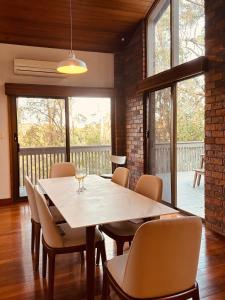 ein Esszimmer mit Tisch und Stühlen und Fenstern in der Unterkunft Luxurious Homely Retreat in Springwood