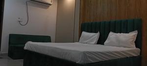 PhūlpurにあるHotel O Ra One Restro & Roomsのベッド(緑のヘッドボード、白い枕付)