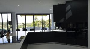 cocina con armarios negros y sala de estar. en Sansuri Resort, en Surin Beach