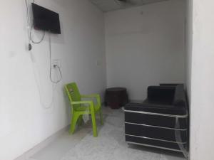 a room with a couch and a green chair at Hotel O Sangam in Sohna