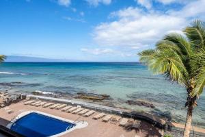 a view of the beach with a swimming pool and a palm tree at Kulakane 310 · KK 310 Updated BeachFront 2BD w AC Pool in Kahana