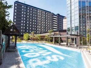 a large swimming pool with a hotel in the background at APA Hotel & Resort Tokyo Bay Makuhari in Chiba