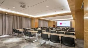 a conference room with tables and chairs and a screen at Echarm Hotel Jinan Railway Station Daming Lake in Jinan