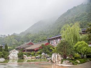 a house with a river in front of a mountain at Xian Huaqingyutang Hotel in Xi'an