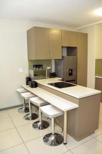 a large kitchen with white counter tops and bar stools at Platinum Heights Merensky in Windhoek