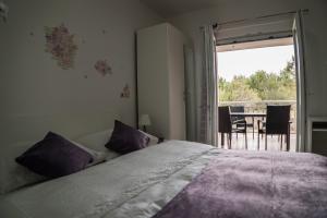 a bedroom with a bed with purple pillows and a balcony at Apartments Malina in Vir