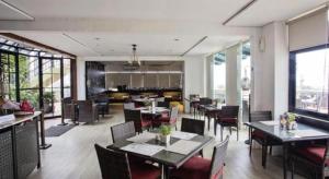 a dining room with tables and chairs and windows at Kenari Tower Hotel in Makassar
