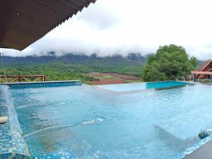 a large swimming pool with a view of a mountain at Brownstone Resort in Mahabaleshwar