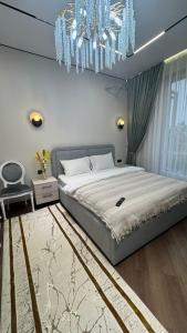 ein Schlafzimmer mit einem großen Bett und einem Kronleuchter in der Unterkunft DeLuXe CLASS HOME in Almaty