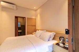 Un dormitorio con una gran cama blanca con almohadas blancas. en AA Inn Kuta Beach, en Ngurah Rai International Airport
