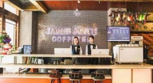 zwei Frauen sitzen mit Laptops an einer Theke in einem Restaurant in der Unterkunft James Joyce Coffetel Xi'an Lingtong The Terracotta Army Huaqingchi University Town Metro Station in Xi'an