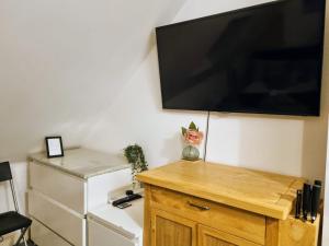 a flat screen tv on a wall above a refrigerator at Loft Flat, near Hampton Court Palace, Free Parking in West Molesey