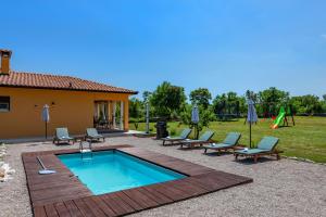 a swimming pool with chairs and a playground at Villa Maria, a charming villa near Labin in Nedeščina