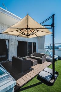 a patio with two couches and a large umbrella at BOND COMFORT HOTEL MIYAJIMAGUCHI - Vacation STAY 80803v in Hatsukaichi +14 photos