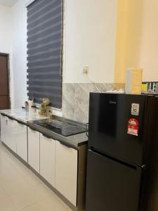 eine Küche mit einem Herd und einem schwarzen Kühlschrank in der Unterkunft Orked Homestay 2 Parit Buntar in Parit Buntar
