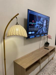 einen Flachbild-TV an einer Wand neben einer Lampe in der Unterkunft Orked Homestay 2 Parit Buntar in Parit Buntar