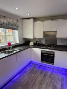 une cuisine avec des armoires blanches et un plancher en bois dans l'établissement Cozy double room stay in Quedgeley, à Quedgeley