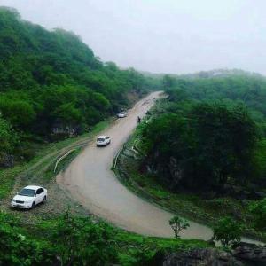 two cars parked on a winding road in the mountains at محمية حوف  +17 photos