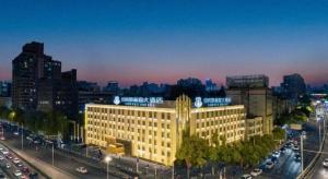 a large building in the middle of a city with traffic at New Beacon Sunyee SPA Hotel in Wuhan