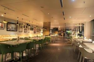 a restaurant with white tables and green chairs at Pomelotel Patra Kuningan Jakarta in Jakarta